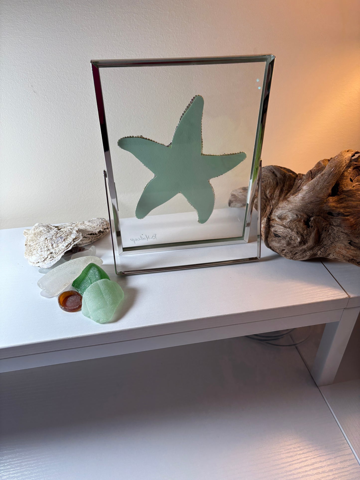 Decorative piece with a starfish in a frame on a white surface.